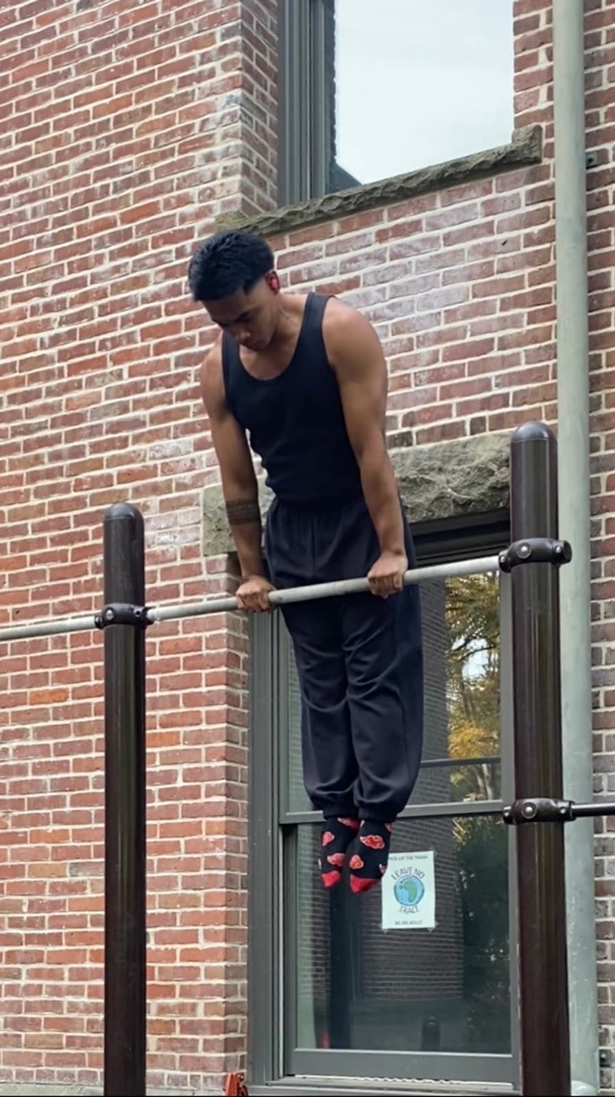Jaimar Sugui, calisthenics coach at MV Calisthenics Seattle, holding a straight bar support on an outdoor bar