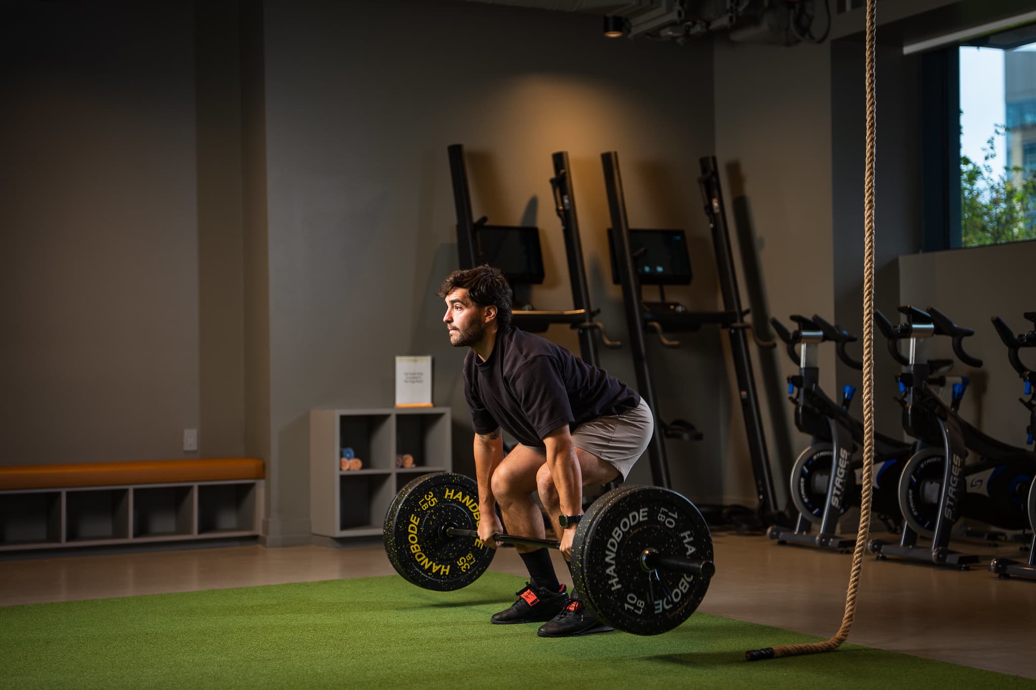 Personal trainer with a barbell in a modern gym, demonstrating focus and strength training.